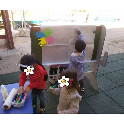 In foto bambino si diverte con i pennarelli e altri bimbi scelgono i pennarelli sul tavolo colorato per la didattica all'aperto